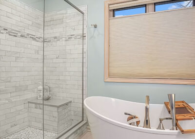 New Bathroom Tub and Shower showing glass shower doors and basin of tub under bathroom window