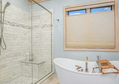 New bath shower with large clear glass doors and interior bench and tub